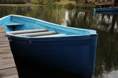Photo of Light blue wooden boat on lake near pier, closeup
