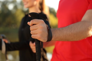 Couple practicing Nordic walking with poles outdoors, closeup