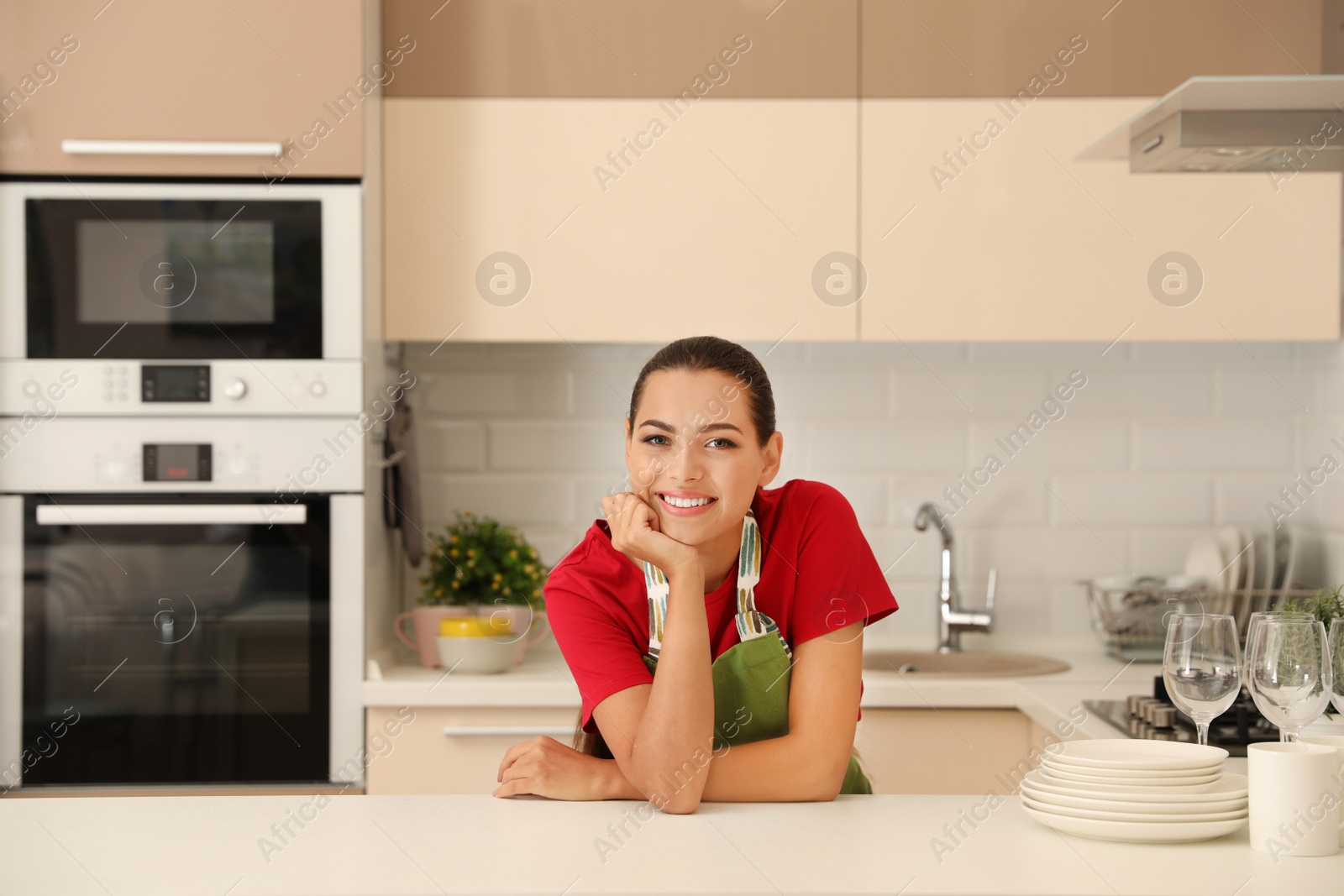 Photo of Beautiful young woman with clean dishes in kitchen