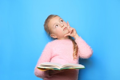 Photo of Little girl with book on light blue background