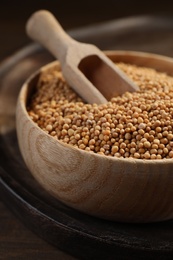 Photo of Mustard seeds with wooden bowl and scoop on tray, closeup