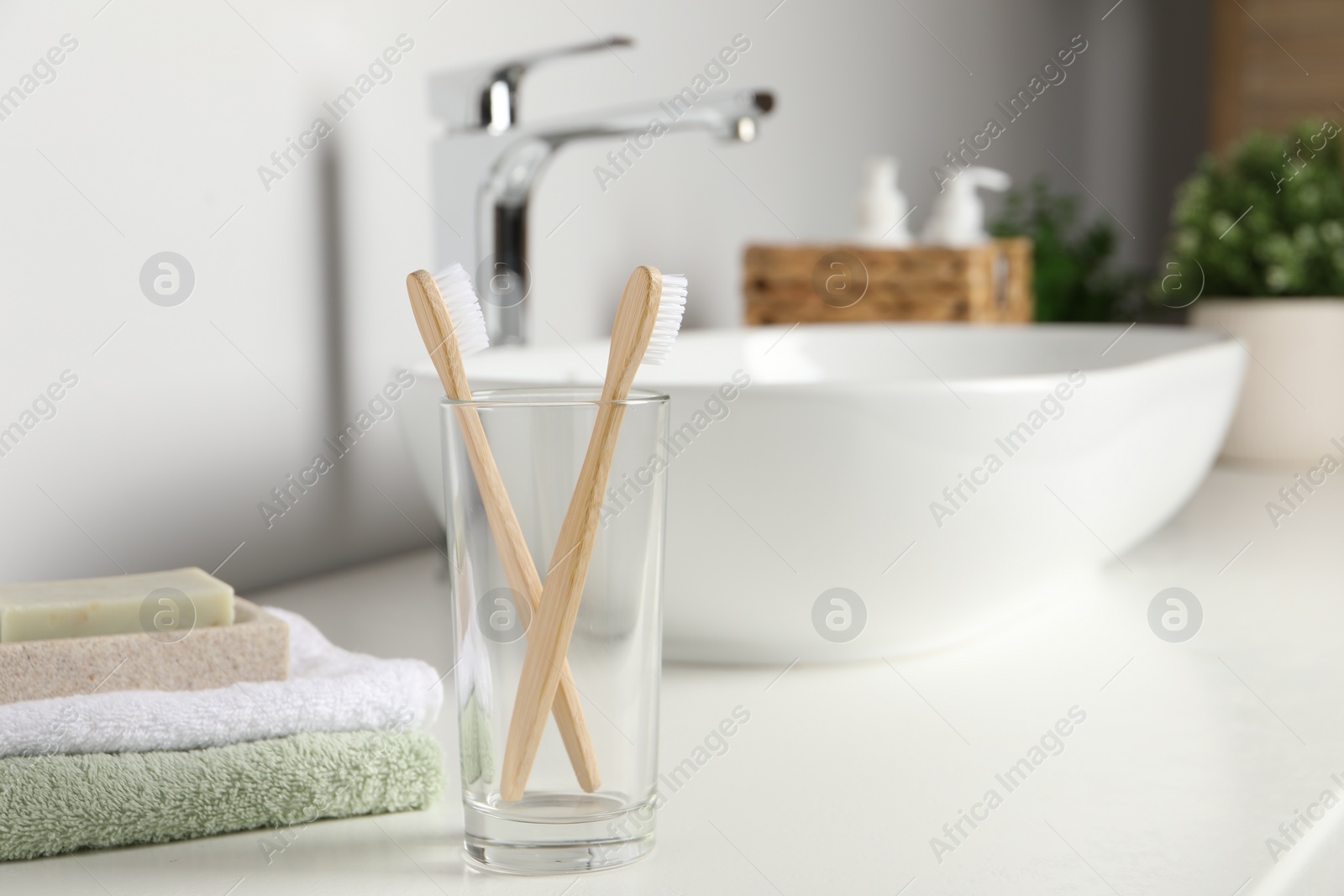 Photo of Bamboo toothbrushes and towels on white countertop in bathroom, space for text