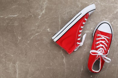 Photo of Pair of red sneakers on grey stone table, flat lay. Space for text
