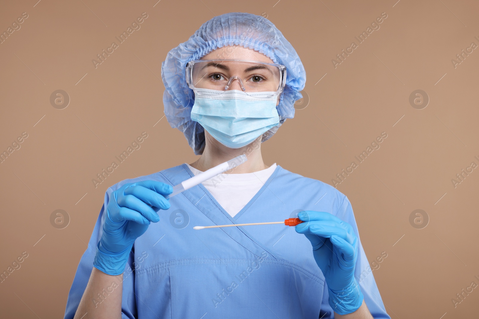 Photo of Laboratory testing. Doctor with cotton swab and tube on light brown background