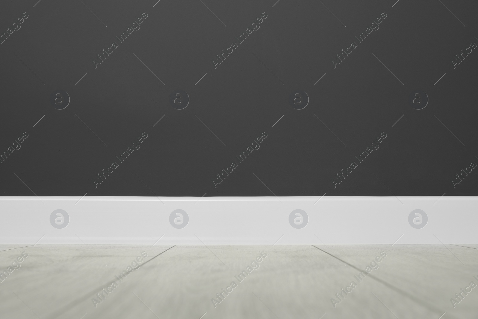 Photo of White plinth on laminated floor near black wall indoors