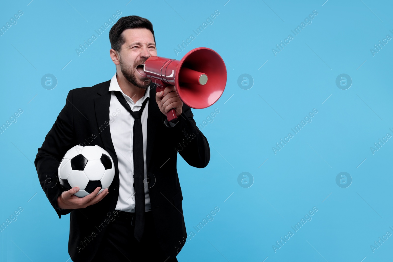 Photo of Emotional sports fan with ball and megaphone celebrating on light blue background. Space for text