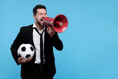 Photo of Emotional sports fan with ball and megaphone celebrating on light blue background. Space for text