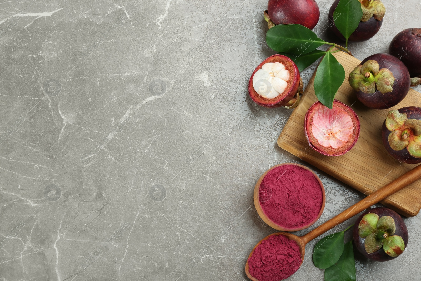 Photo of Purple mangosteen powder and fruits on grey marble table, flat lay. Space for text