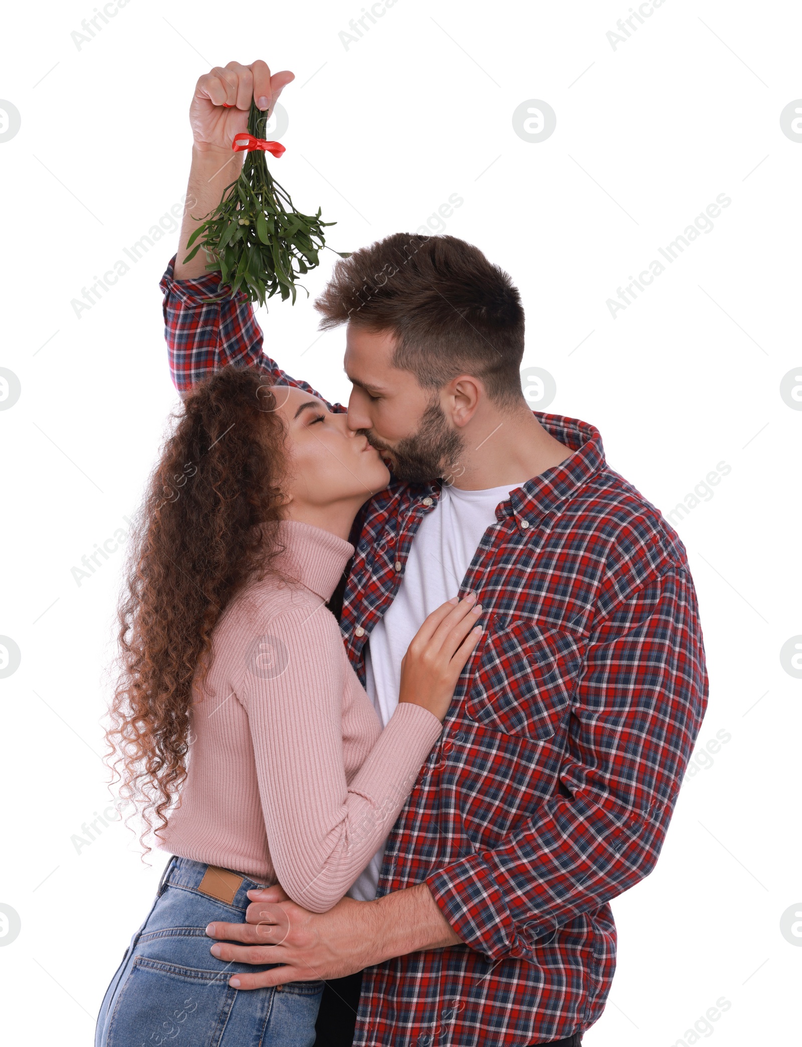 Photo of Happy couple kissing under mistletoe bunch on white background