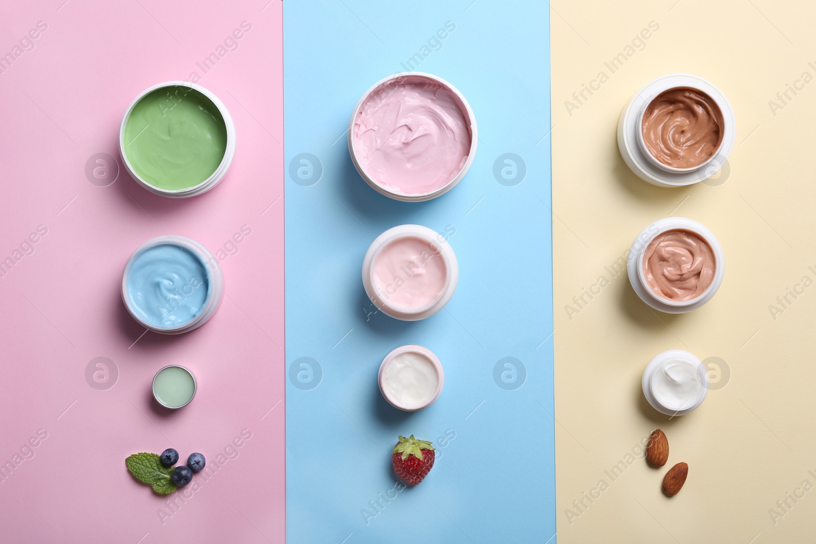 Photo of Flat lay composition with jars of body cream on color background