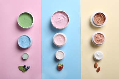 Photo of Flat lay composition with jars of body cream on color background