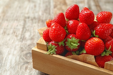 Photo of Crate with ripe strawberries on wooden background, closeup