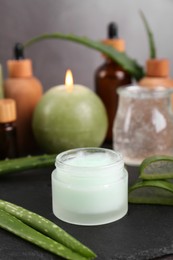 Jar of natural gel and fresh aloe vera leaves on slate board