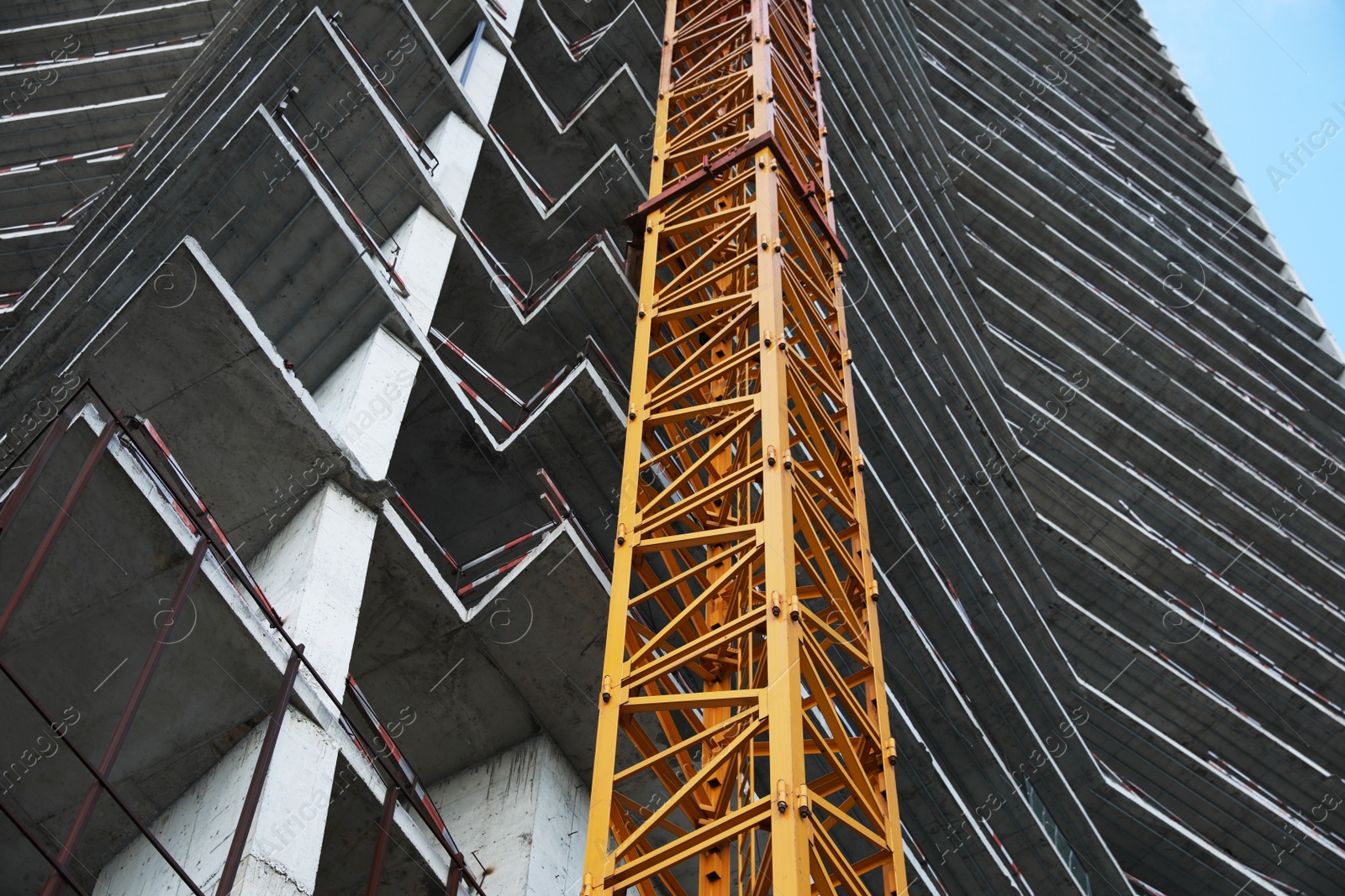 Photo of Construction site with tower crane near unfinished building, low angle view