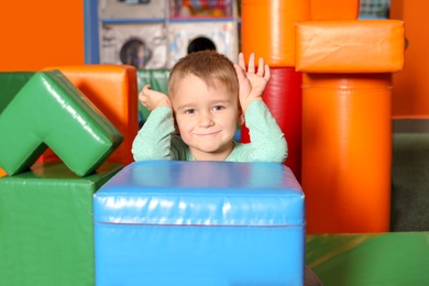 Cute child playing with colorful building blocks indoors