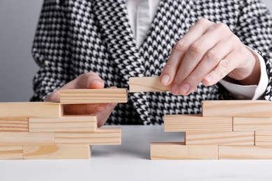 Photo of Businesswoman building bridge with wooden blocks at table, closeup. Connection, relationships and deal concept