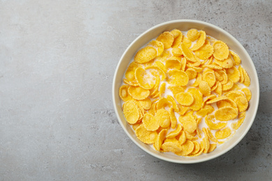 Tasty crispy corn flakes with milk on light grey table, top view. Space for text