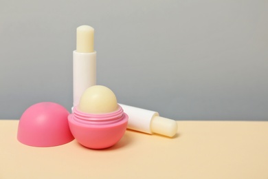 Hygienic lipsticks and balms on table against grey background