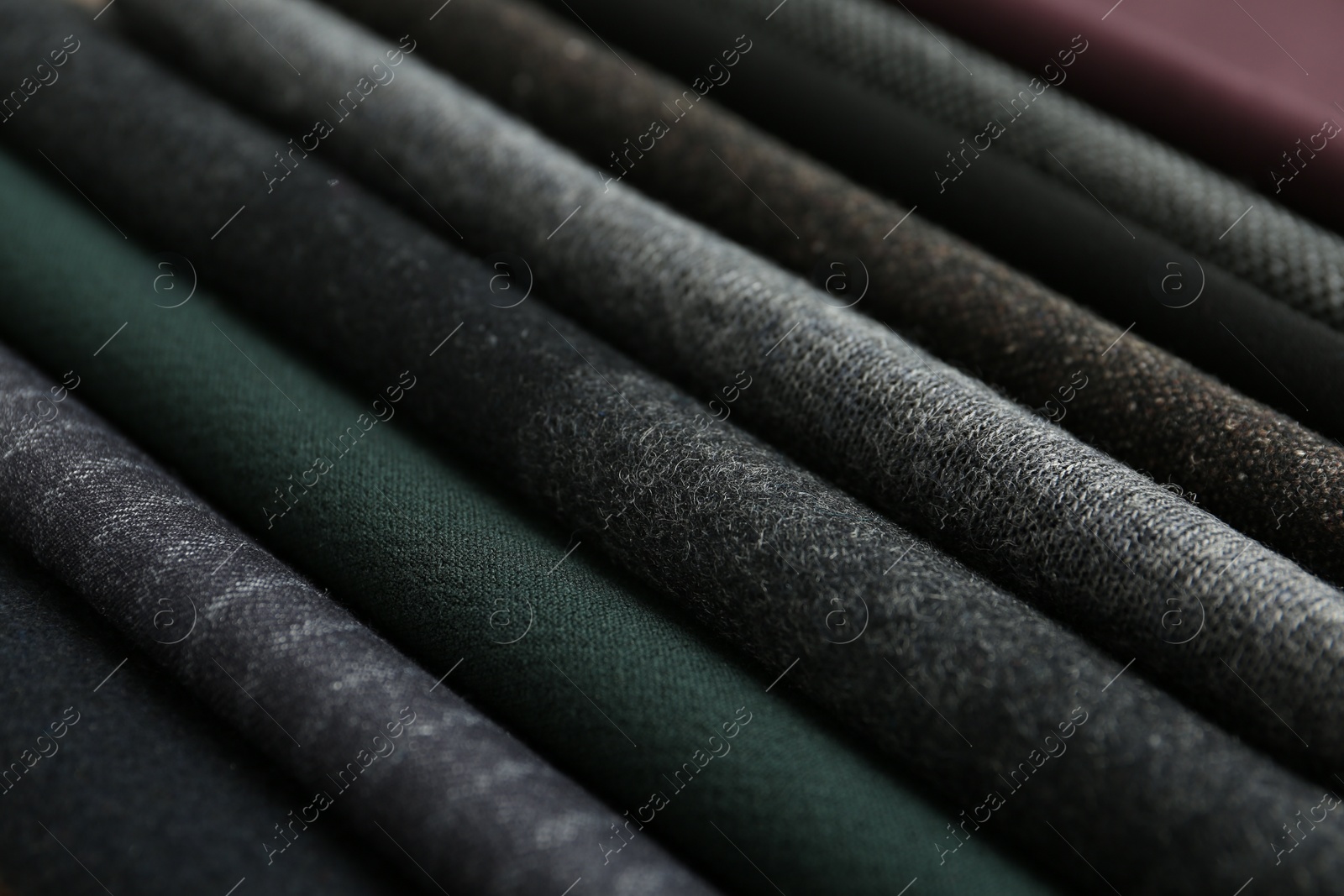 Photo of Stack of different fabric samples as background, closeup. Textile texture