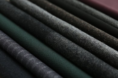 Stack of different fabric samples as background, closeup. Textile texture