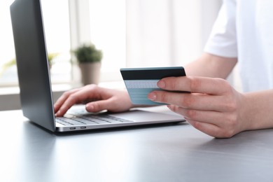 Photo of Online payment. Woman with laptop and credit card at white table, closeup