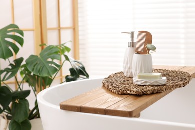 Photo of Different personal care products and accessories on bath tub in bathroom