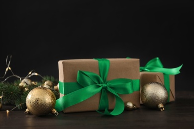 Photo of Gift boxes with Christmas balls and fir tree branches on wooden table