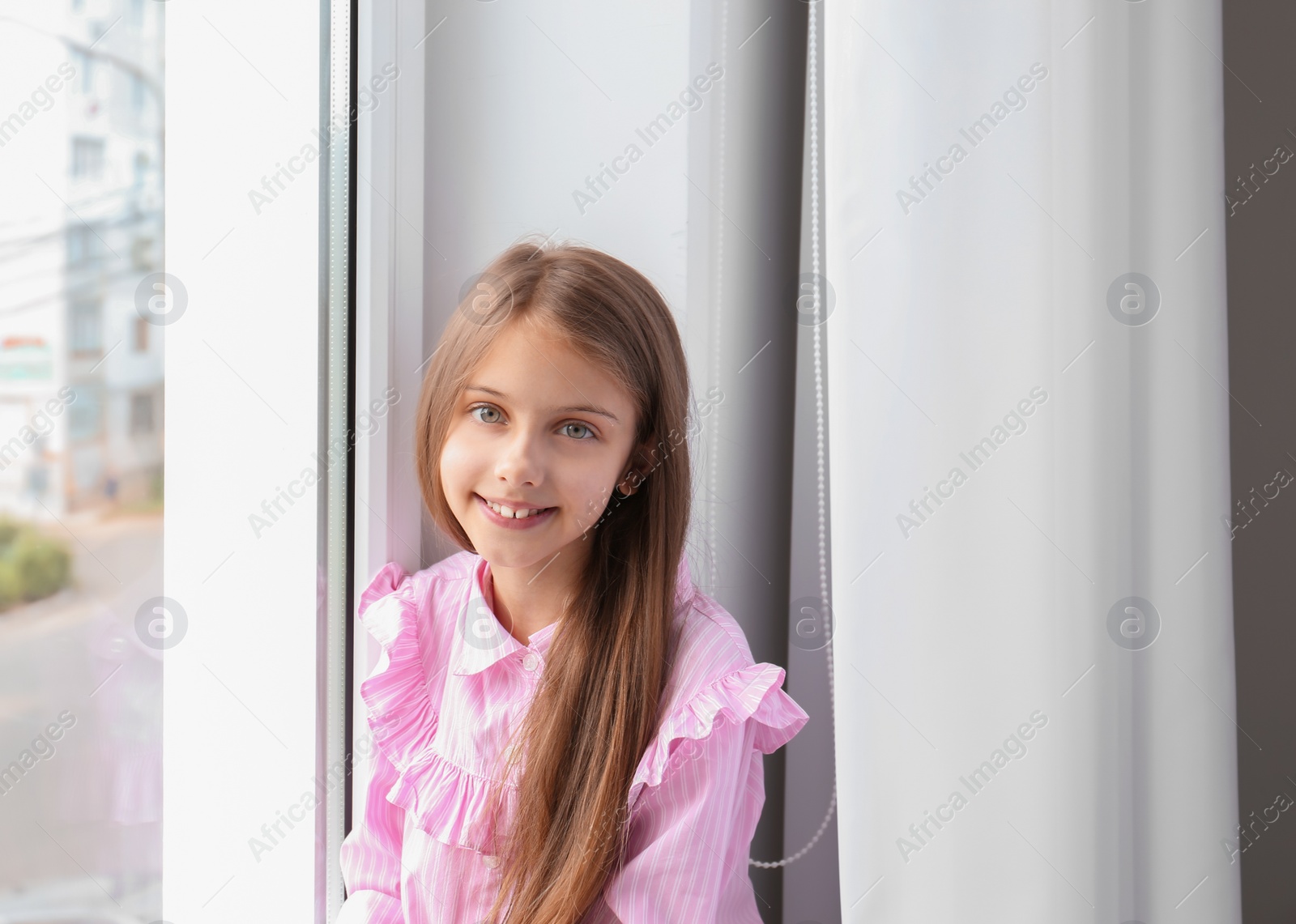 Photo of Cute little girl near window in room