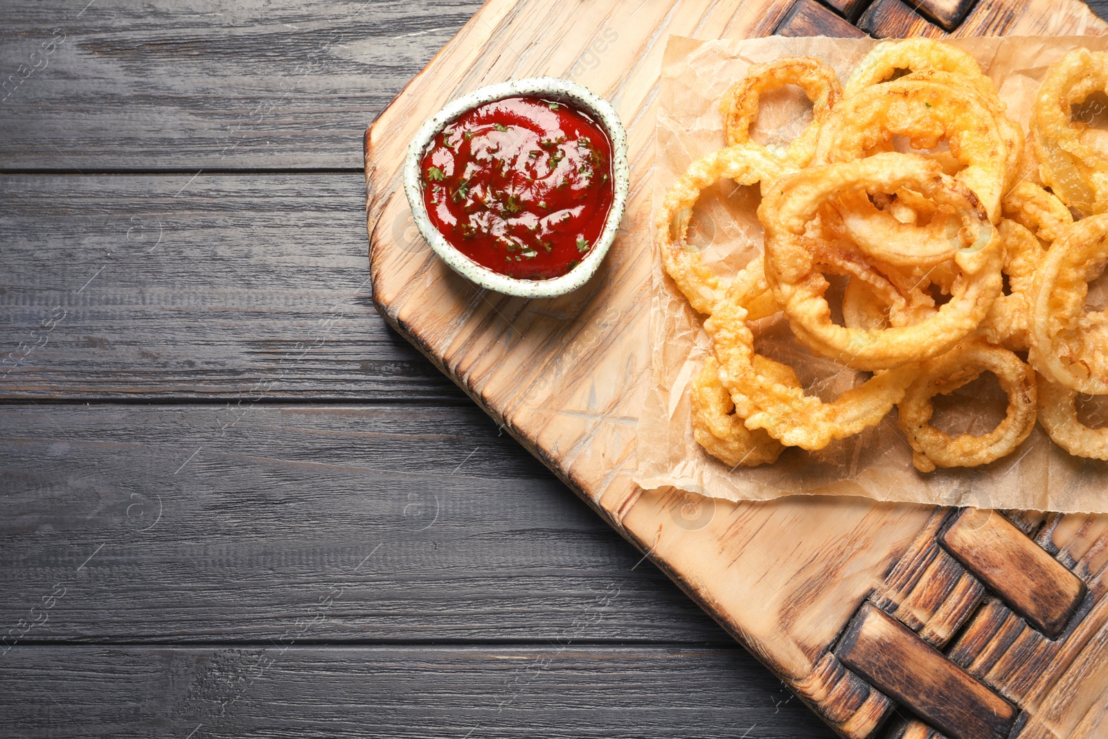 Photo of Homemade crunchy fried onion rings and sauce on wooden background, top view. Space for text