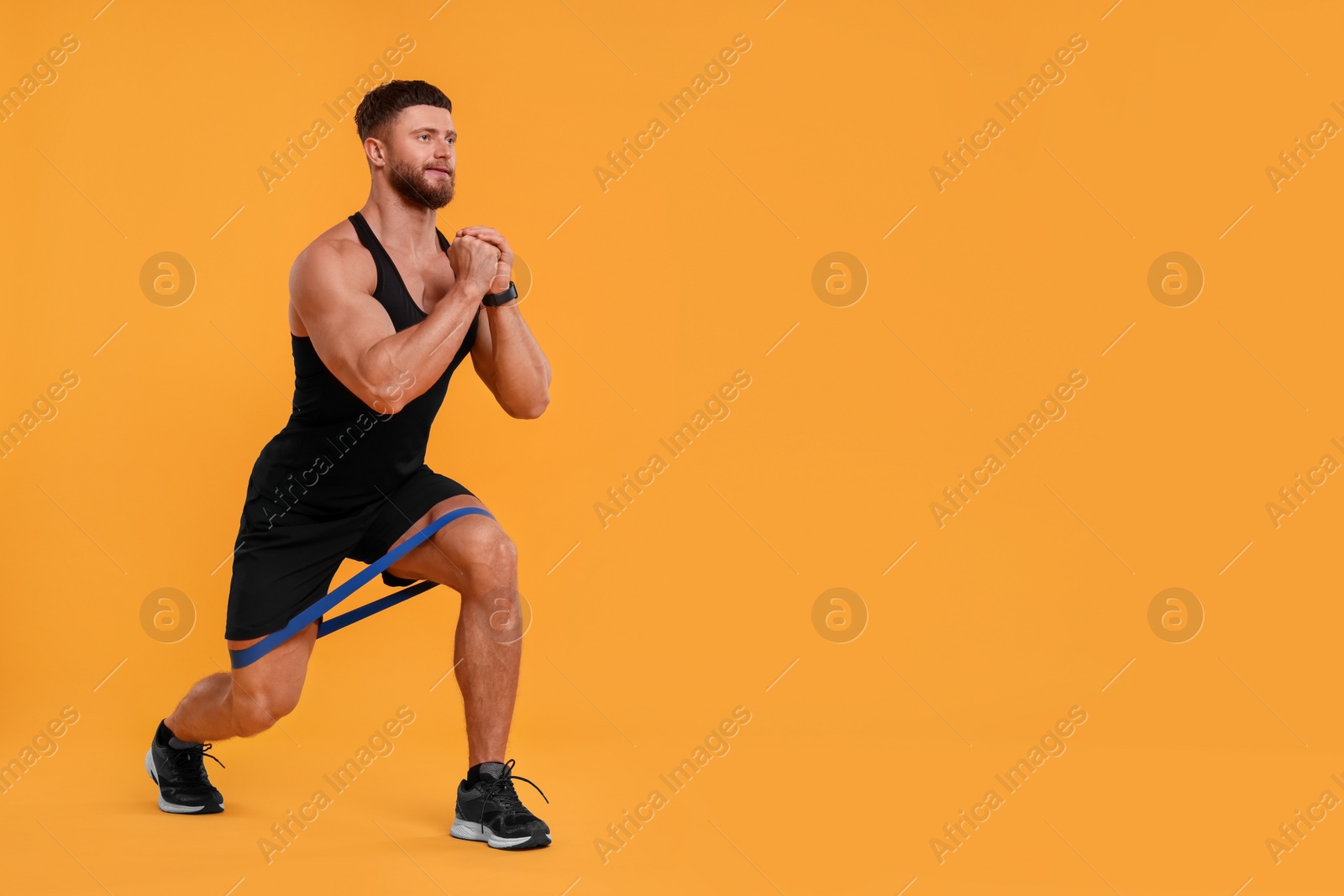 Photo of Young man exercising with elastic resistance band on orange background. Space for text