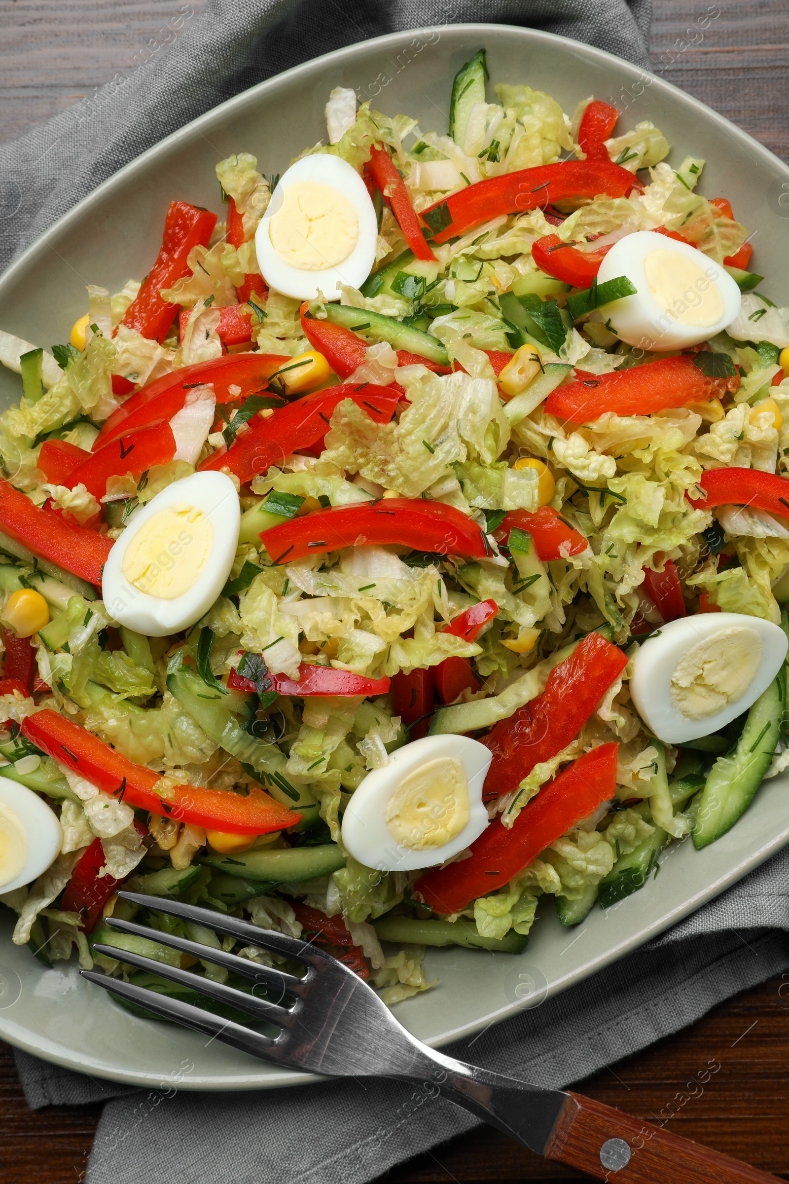 Photo of Delicious salad with Chinese cabbage and quail eggs served on wooden table, top view