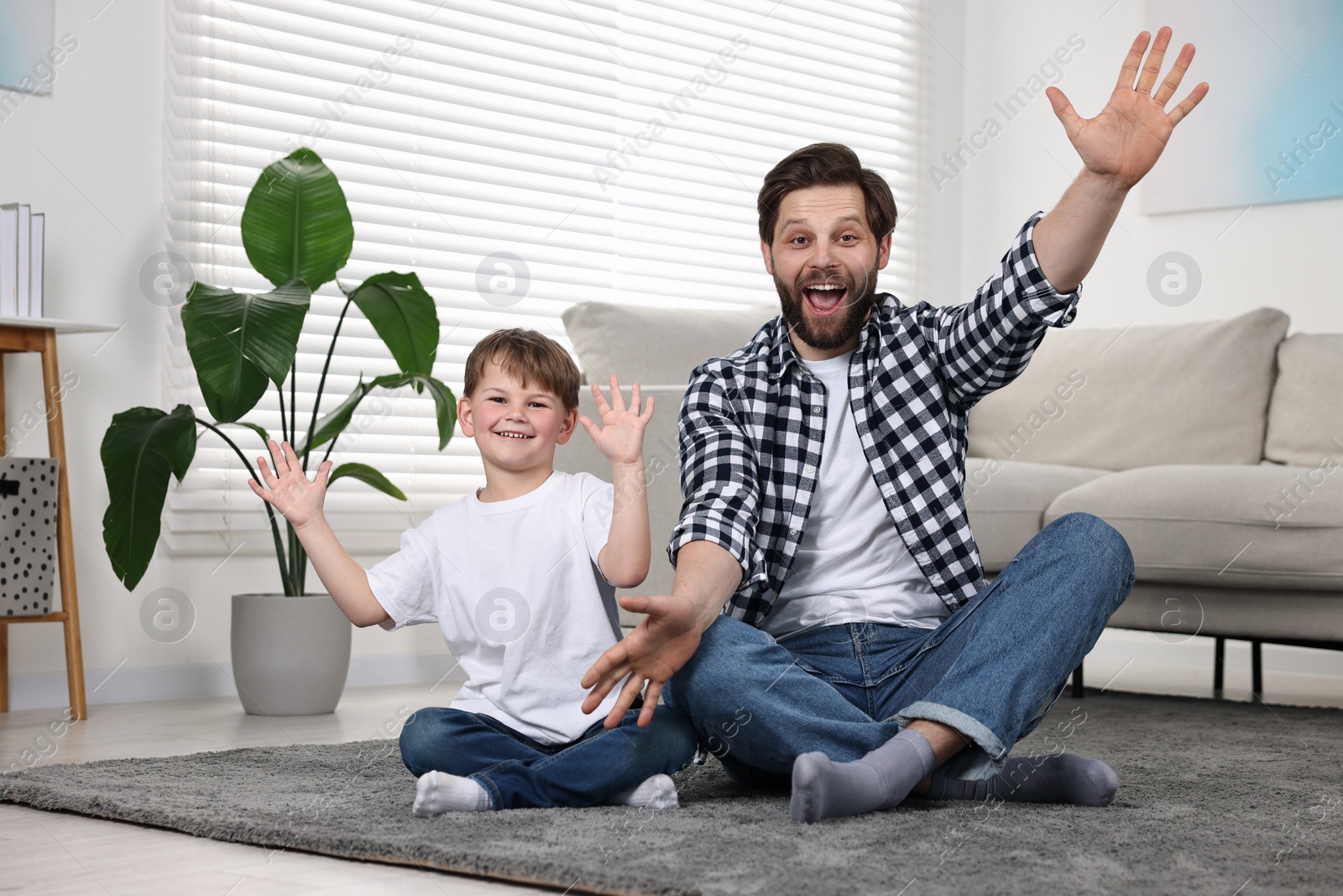 Photo of Happy dad and son having fun on carpet at home