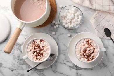 Photo of Aromatic hot chocolate with marshmallows and cocoa powder served on white marble table, flat lay