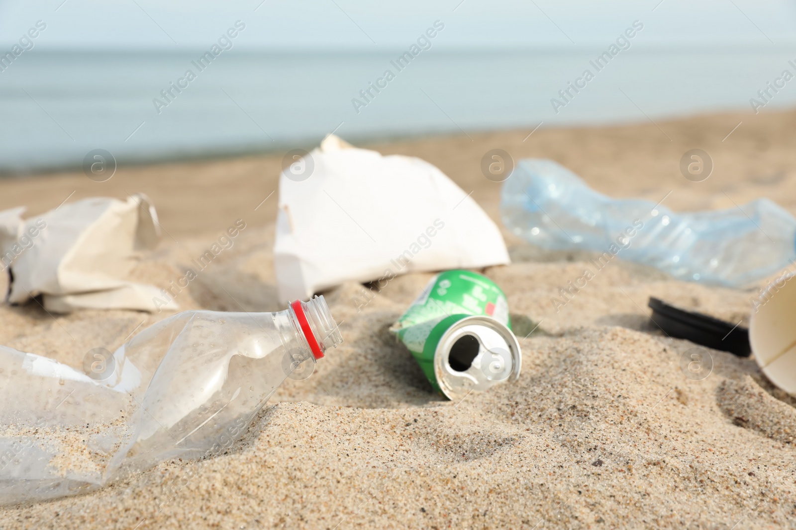 Photo of Garbage scattered on beach near sea, closeup. Recycling problem