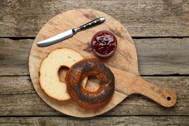 Photo of Delicious fresh halved bagel and jam on wooden table, top view