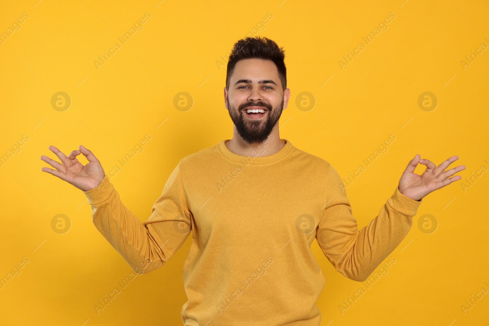 Photo of Young man meditating on yellow background. Zen concept