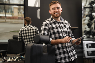 Photo of Young business owner with tablet in barber shop