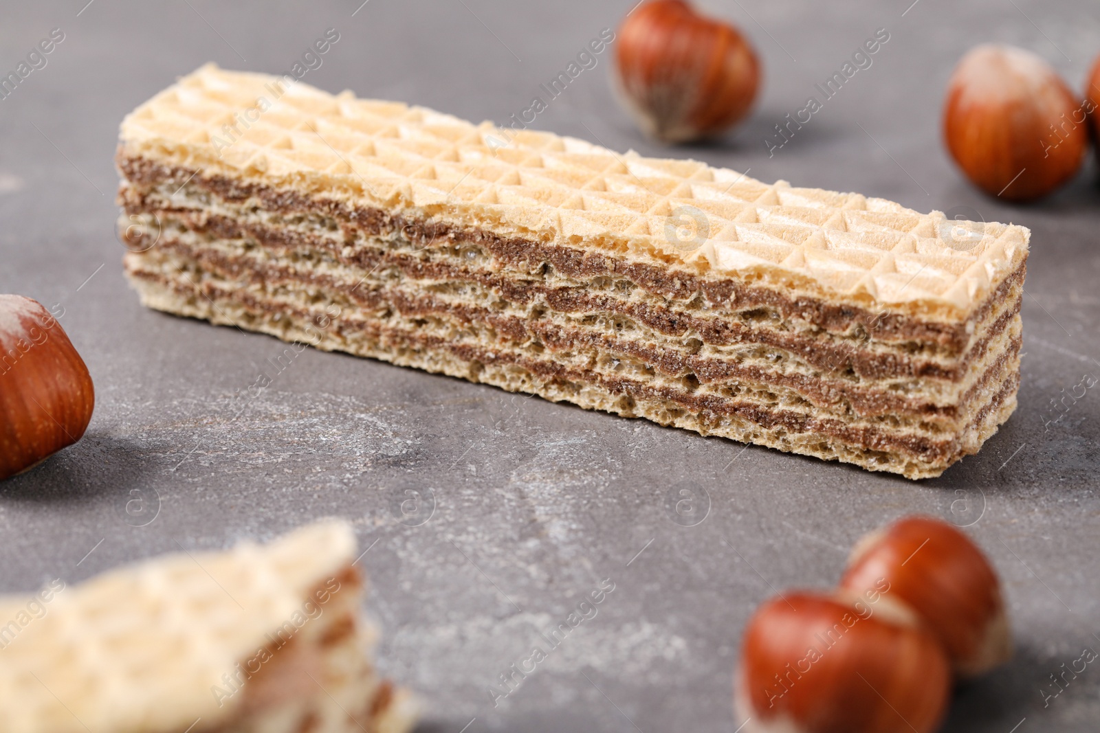 Photo of Delicious wafers with hazelnuts on grey stone background