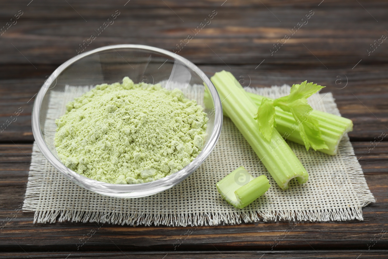 Photo of Natural celery powder in bowl and fresh stalks on wooden table