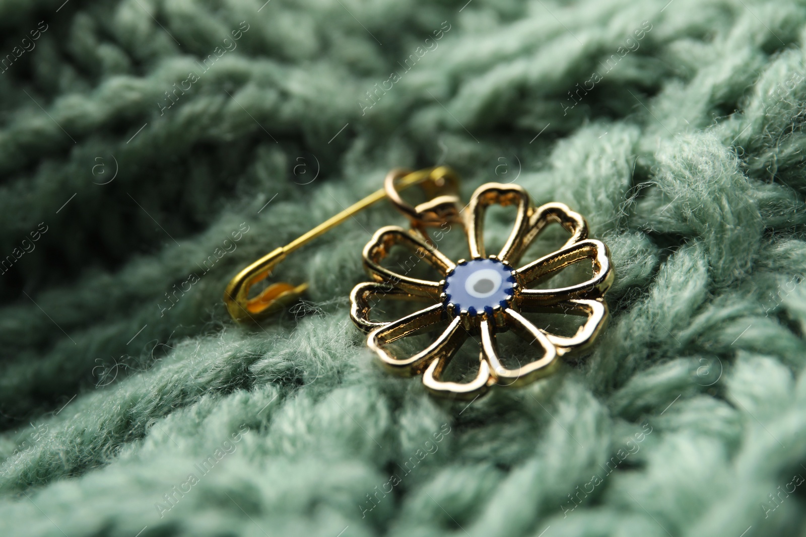 Photo of Evil eye safety pin on knitted clothing, closeup