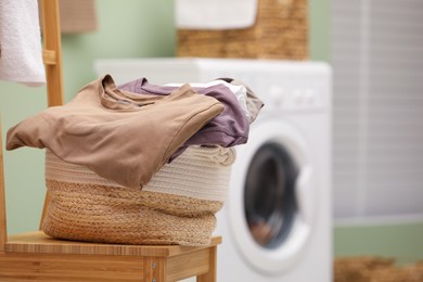Photo of Laundry basket filled with clothes on chair in bathroom, closeup. Space for text