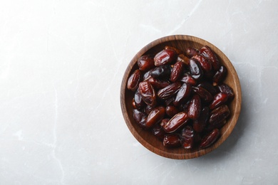 Photo of Bowl of sweet dates on grey background, top view with space for text. Dried fruit as healthy snack