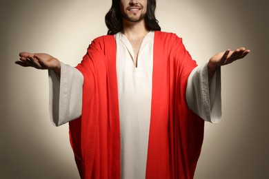 Photo of Jesus Christ with outstretched arms on beige background, closeup