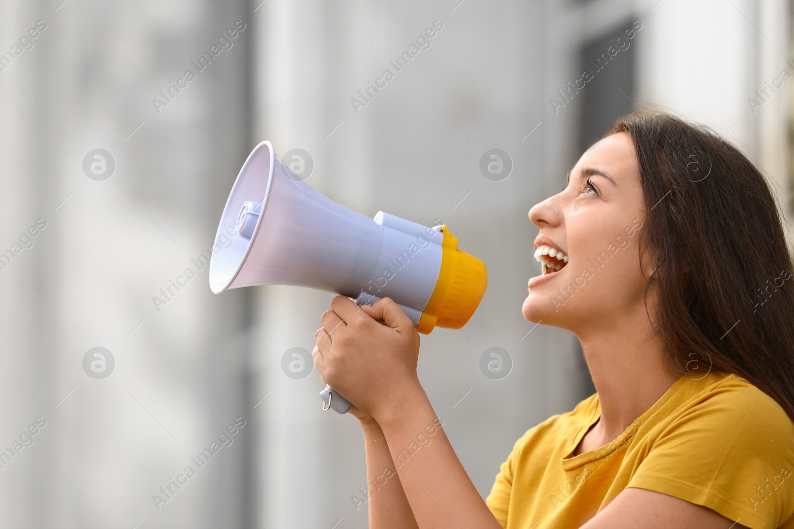 Image of Emotional young woman with megaphone outdoors. Protest leader