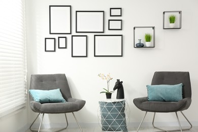 Photo of Stylish room interior with empty frames hanging on white wall