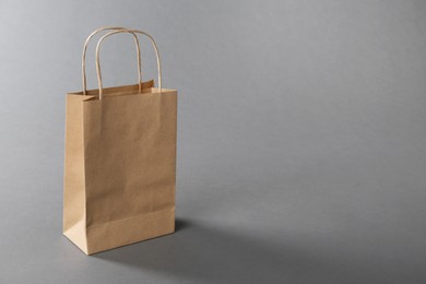 One kraft paper bag on grey background, space for text. Mockup for design