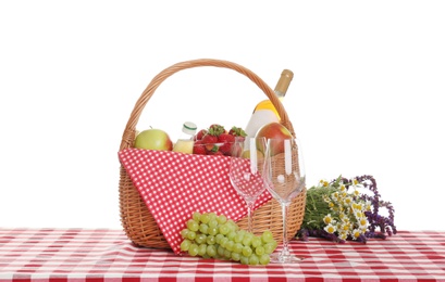 Photo of Picnic basket with wine and food on tablecloth against white background