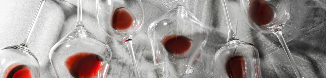 Image of Glasses with red wine on grey background, flat lay. Banner design