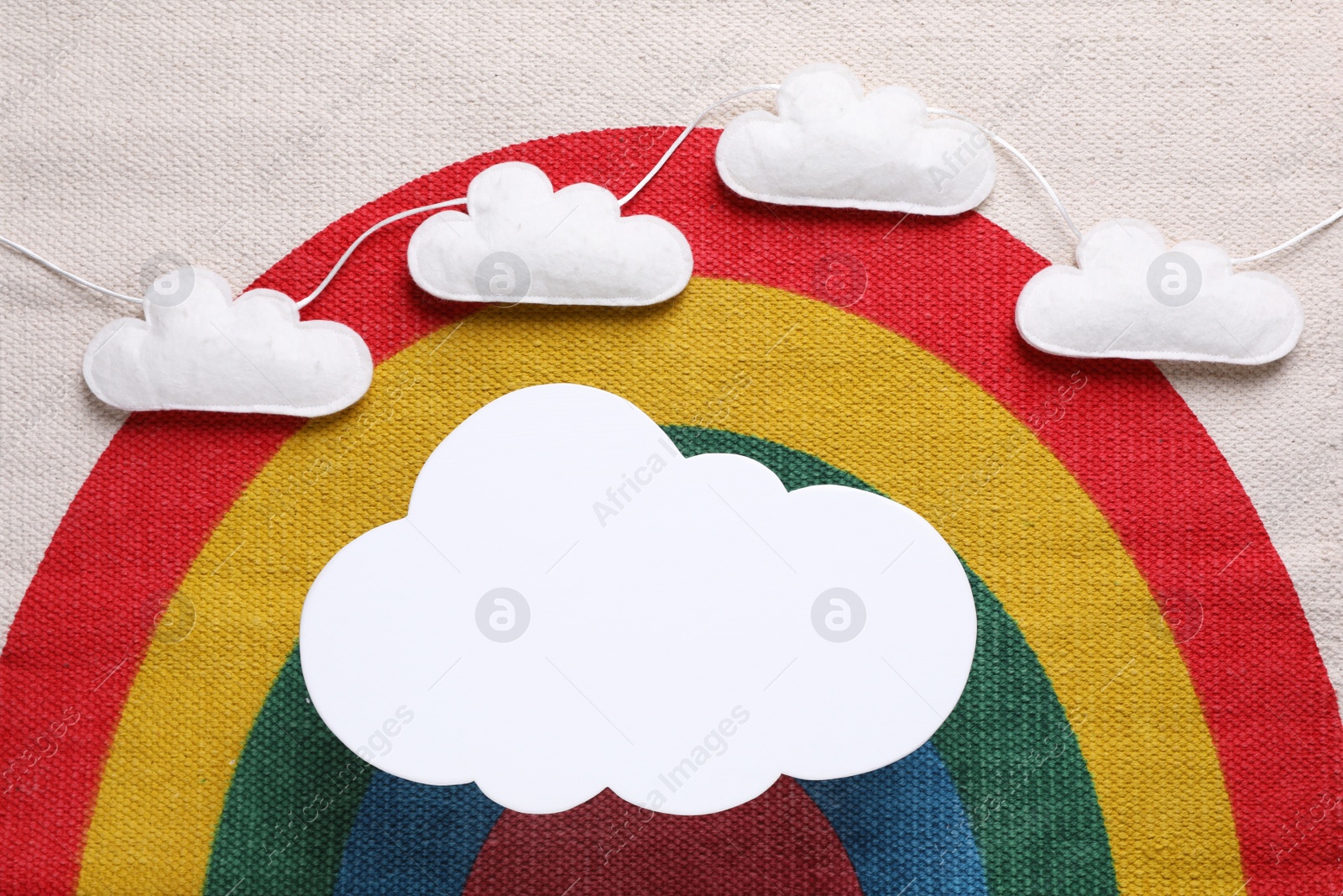 Photo of Cloud shaped child's night lamp on fabric with rainbow pattern, flat lay