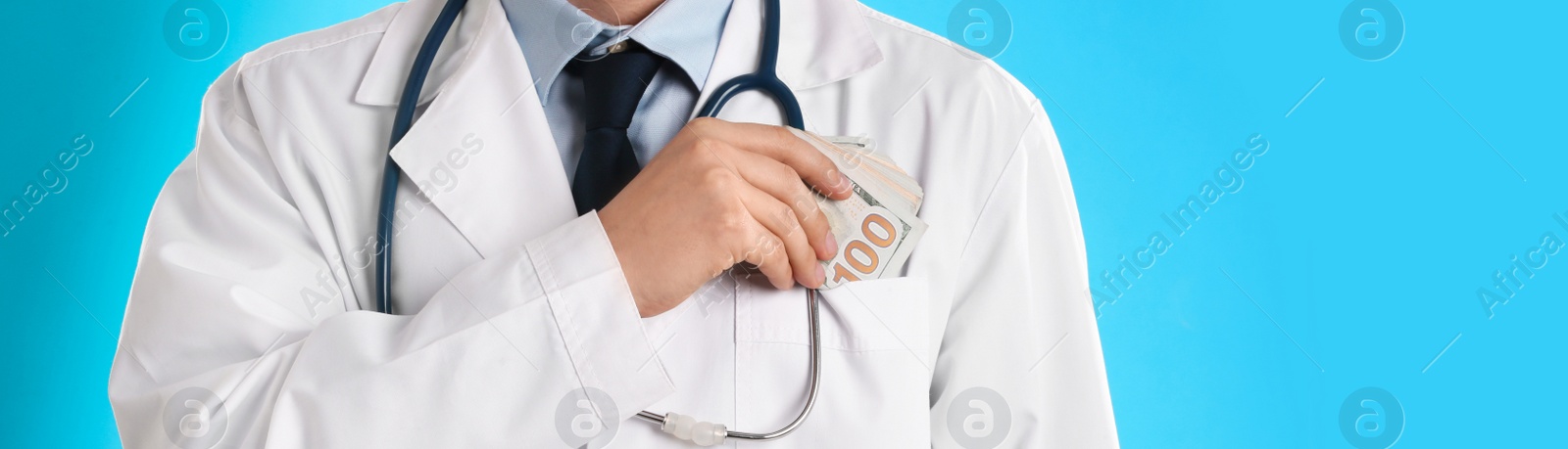 Image of Doctor putting bribe into pocket on light blue background, closeup. Banner design